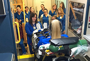 A participant volunteers as the injured person loaded on to an ambulance, as classmates watch the the demo.